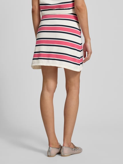 Vrouwenmodel draagt Eng anliegender Mini-Rock aus reiner Baumwolle Modell 'AMOUR' van Selected Femme met all-over gestreepte look, regular fit, minilengte, elastisch boord en rechte zoom, knitwear van puur katoen, Ganzkörperansicht Rückansicht.