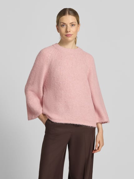 Frauenmodel trägt Strickpullover mit Raglanärmeln von FREE/QUENT in Rosa, gerader Schnitt, grobe Textur, Nahaufnahme Oberkörper.