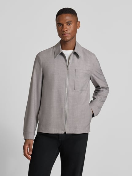 Männermodel trägt Regular Fit Jacke mit Viskose-Anteil Modell 'Jerson' von Drykorn in Hellgrau, sichtbare Brusttasche und Reißverschluss, Ganzkörperansicht von vorne.