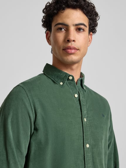 Männermodel trägt Freizeithemd mit Label-Stitching von Superdry in Grün aus reiner Baumwolle, Regular-Fit, Button-Down-Kragen, Nahaufnahme Oberkörper.