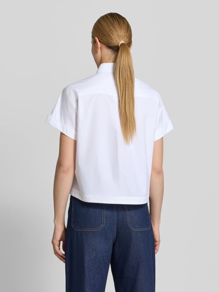 Vrouwenmodel draagt Boxy Fit Bluse mit Brusttasche van Luisa Cerano in wit katoen met borstzak, overhemdkraag, knoopsluiting, omgeslagen mouwen, ruglengte 57 cm, mouwlengte 17 cm, geheel van achteren.