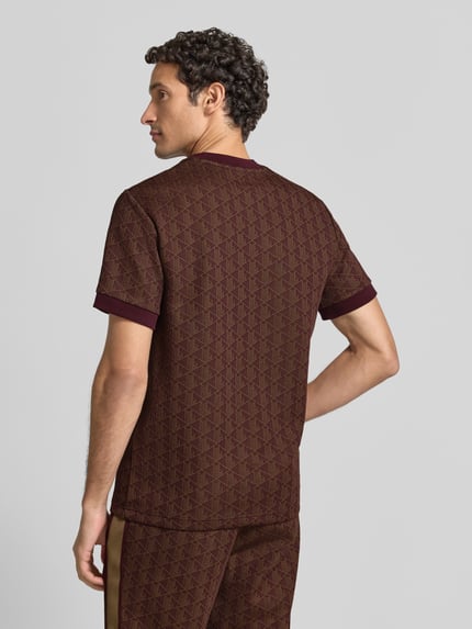 Männermodel trägt Regular Fit T-Shirt aus Baumwoll-Mix von Lacoste in Braun mit Muster und gerippten Bündchen, Ganzkörperansicht Rückansicht.