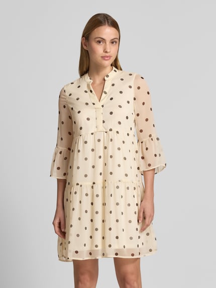 Vrouwenmodel draagt Tailliertes Minikleid mit V-Ausschnitt Modell 'SMILLA' van Vero Moda, look: all-over stippenmotief, getailleerd, minilengte, V-hals, volantdetails, volantmouwen, materiaalverwerking: chiffon, Ganzkörperansicht van voren.
