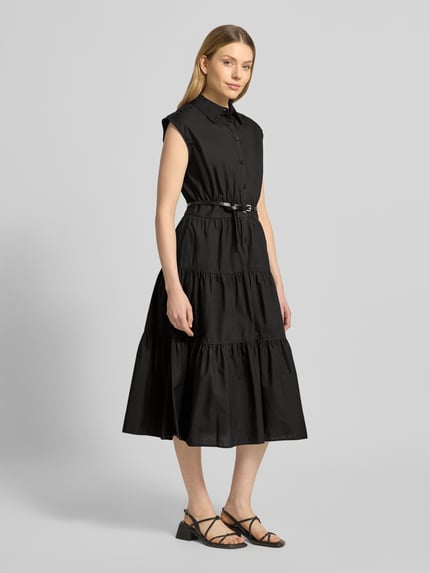 Frauenmodel trägt Hemdblusenkleid mit Gürtel und Knopfleiste von MICHAEL Michael Kors in Schwarz, reine Baumwolle, tailliert, Midilänge, Volantsaum, ganzkörperansicht von vorne.