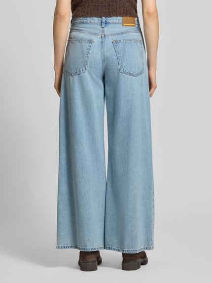 Frauenmodel trägt Loose-Fit Jeans aus Baumwoll-Lyocell-Mix Modell 'ASTRAEAAS' von Armedangels in heller Denim-Optik, Label-Patch, 5-Pocket-Design, Ganzkörperansicht Rückansicht.