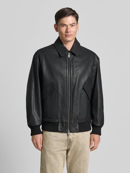 Męski model nosi Regular Fit Lederjacke aus echtem Ziegenleder Modell 'JOSUAL' od BOSS Orange, czarna, teksturowana powierzchnia, Ganzkörperansicht von vorne.