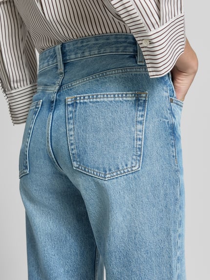 Frauenmodel trägt Straight Fit Jeans aus reiner Baumwolle Modell 'MIAMI' von MANGO, hellblau, 5-Pocket-Design, Nahaufnahme Rückansicht.