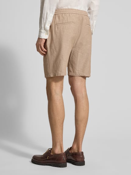 Männermodel trägt Shorts aus Baumwoll-Leinen-Mix mit elastischem Bund von Scotch & Soda, regular fit, beige, Ganzkörperansicht Rückansicht