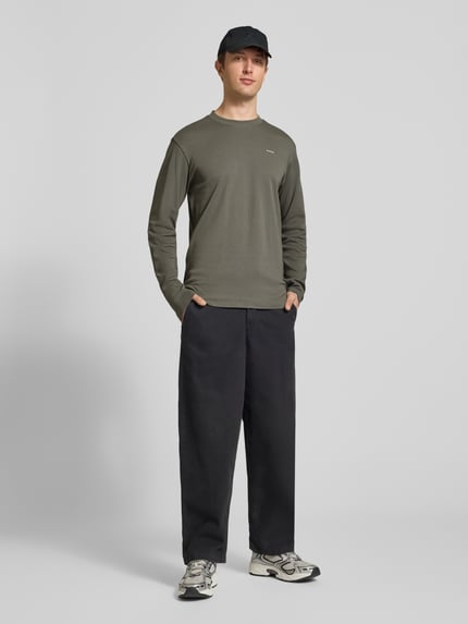 Männermodel trägt olivgrünes Langarmshirt mit kleinem Logo-Schriftzug von G-Star RAW, strukturierter Jersey, Ganzkörperansicht von vorne.