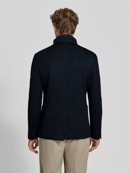 Männermodel trägt Slim Fit Sakko mit Woll-Anteil Modell 'Hypetar' von JOOP! COLLECTION in Dunkelblau, glatte Struktur, Ganzkörperansicht Rückansicht.