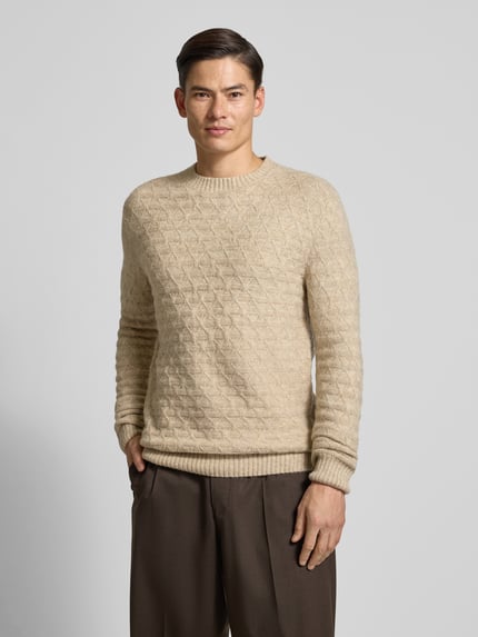 Męski model nosi Sweter z dzianiny z prążkowanymi wykończeniami Model 'BLASIMON' od Jack & Jones Premium, mieszanka materiałów z dodatkiem wełny, krój regular fit, okrągły dekolt, kolor beżowy, widoczne detale faktury, długość tyłu 71 cm, długość rękawów 72 cm, zdjęcie całej sylwetki od przodu.