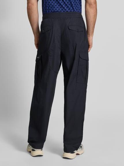 Männermodel trägt Wide Fit Cargo-Hose mit Baumwoll-Anteil von Armani Exchange, dunkles Material mit Cargo-Taschen, Ganzkörperansicht Rückansicht. Material-Mix mit Baumwoll-Anteil, elastischer Bund, Bundweite 45 cm, Innenbeinlänge 78 cm.