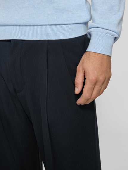 Männermodel trägt Stoffhose mit Bügelfalte Modell 'LEEK' von DRYKORN, Dunkelblau, Material-Mix, Nahaufnahme Oberkörper, Kontext Herrenmode.