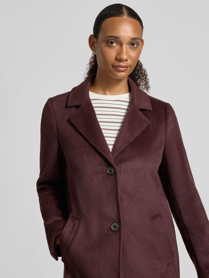 Frauenmodel trägt Regular Fit Mantel mit Woll-Anteil von s.Oliver RED LABEL in Dunkelrot, glatte Textur, Nahaufnahme Oberkörper.