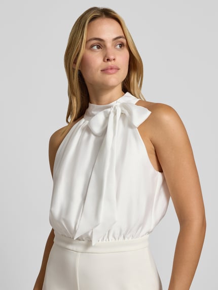 Frauenmodel trägt Jumpsuit mit Stehkragen von SWING in Creme, taillierte Passform, Zierschleife, ärmellos, Nahaufnahme Oberkörper.