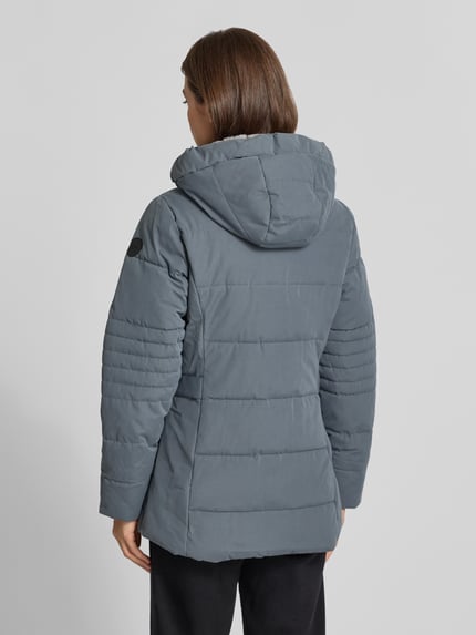 Frauenmodel trägt Jacke mit Kapuze und Label-Patch von G.I.G.A. DX in Blau, Steppstruktur, Material-Mix, Ganzkörperansicht Rückansicht.