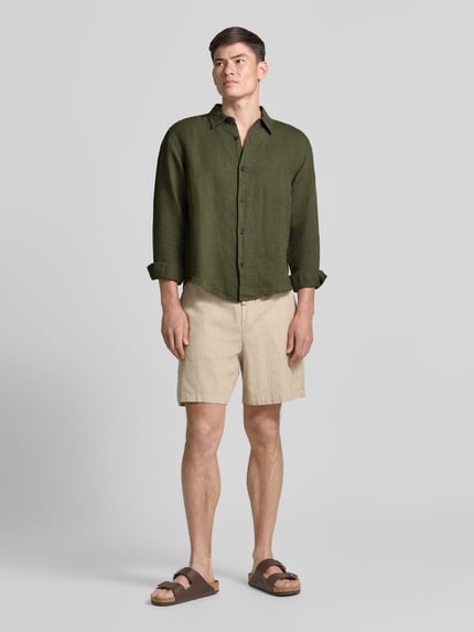 Männermodel trägt Regular Fit Leinenhemd mit Kentkragen von GAP in Grün, reine Leinen, Knopfleiste, Ganzkörperansicht von vorne.