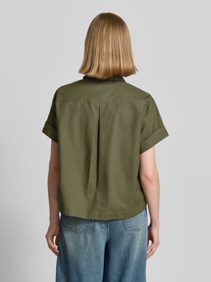 Frauenmodel trägt Boxy Fit Bluse mit Brusttasche von Luisa Cerano aus reiner Baumwolle in Olivgrün, kurze Ärmel, Rückenlänge 57 cm, Ärmel mit Aufschlag, Ganzkörperansicht Rückansicht.