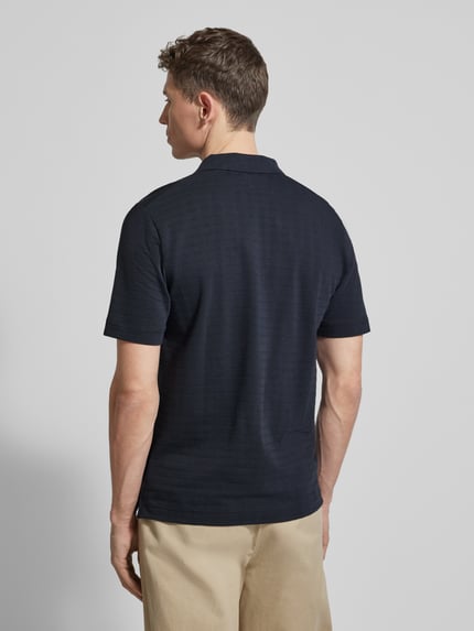Männermodel trägt Regular Fit Poloshirt aus reiner Baumwolle von Marc O'Polo, dunkelblau, Gitterkaro Struktur, Ganzkörperansicht Rückansicht.