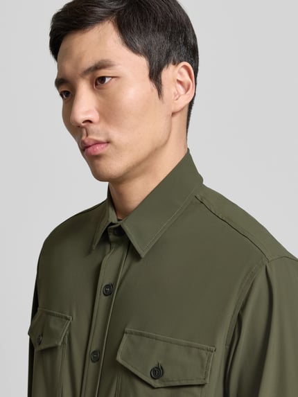 Männermodel trägt 'Hemdjacke mit Knopfleiste' von CRUNA in olivgrün, Regular Fit, Brusttaschen, Materialmix, Nahaufnahme Oberkörper.