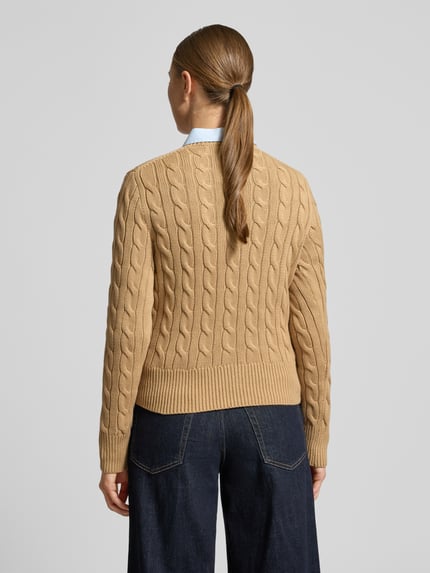 Frauenmodel trägt Slim Fit Strickjacke mit Logo-Stitching von Polo Ralph Lauren aus beiger Baumwolle mit Zopfmustertextur, Ganzkörperansicht Rückansicht.