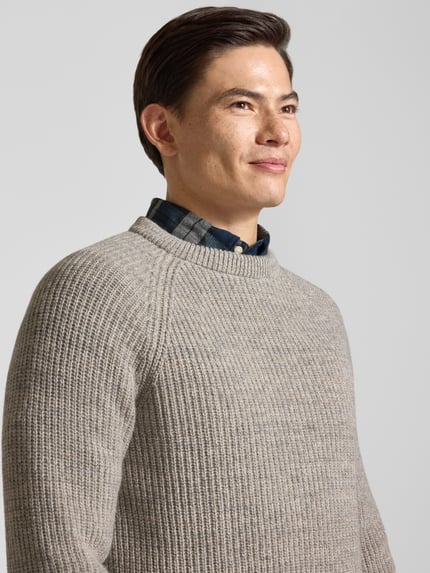 Männermodel trägt Strickpullover aus reiner Baumwolle Modell 'BARBOUR HORSEFORD' von BARBOUR in Melange-Strickoptik, Nahaufnahme Oberkörper.