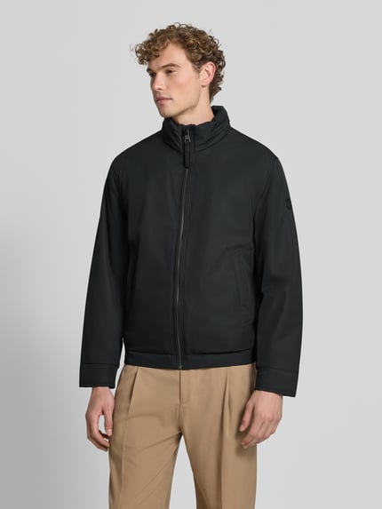 Mężczyzna model nosi Regular Fit Steppjacke mit Stehkragen Modell 'LIGHT' od Strellson, kurtka pikowana w kolorze czarnym, gładka tekstura, Ganzkörperansicht von vorne, kurtka męska Strellson.