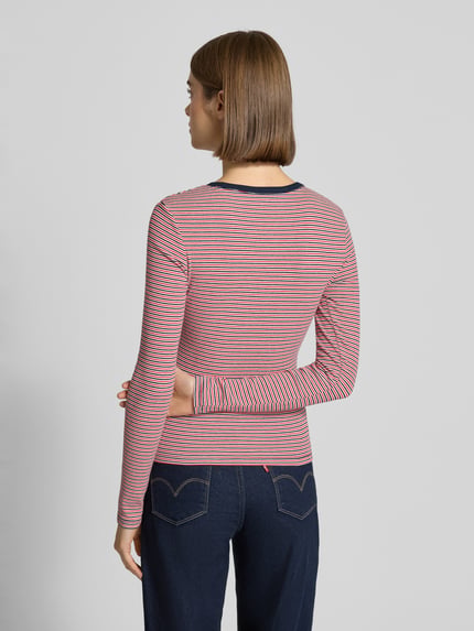 Frauenmodel trägt Slim Fit Langarmshirt aus Baumwoll-Mix von Tommy Jeans, mehrfarbig gestreift, Logo-Detail, Feinstruktur, Ganzkörperansicht Rückansicht.