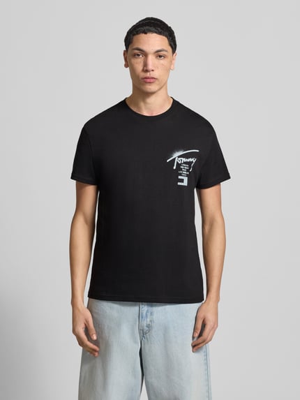 Männermodel trägt Regular Fit T-Shirt aus reiner Baumwolle von Tommy Jeans in Optik: Unifarben mit Label-Print, Ganzkörperansicht von vorne.