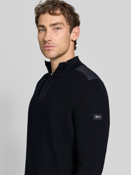 Männermodel trägt gebreide pullover met schoudervullingen van bugatti in donkerblauw, puur katoen, recht model, schipperskraag, ribboorden, ruglengte maat M 68 cm, mouwlengte maat M 70 cm, detailaufnahme bovenlichaam.