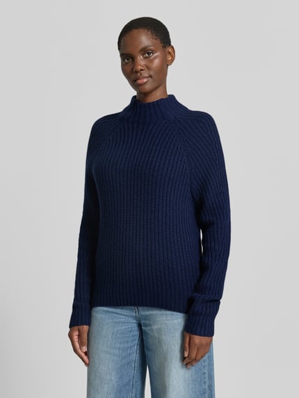 Frauenmodel trägt dunkelblauen Strickpullover aus Kaschmir-Baumwoll-Mix Modell 'LONA' von 0039 Italy, grobe Struktur, Ganzkörperansicht von vorne, Damen Regular Fit, Stehkragen, Rückenlänge 60 cm, Ärmellänge 78 cm.