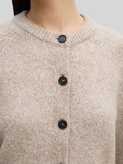 Frauenmodel trägt Strickjacke aus Alpaka Wolle mit Rollsaum von Marc O'Polo im Melange-Look, Struktur, Rundhals, Nahaufnahme Oberkörper.