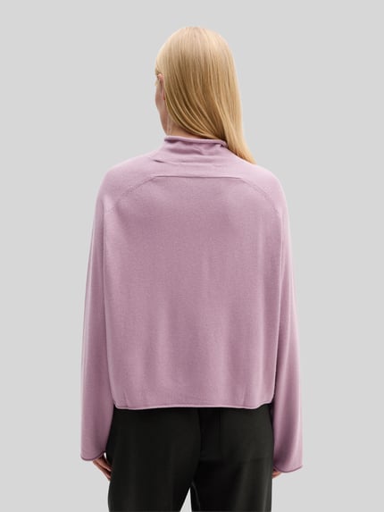 Frauenmodel trägt Rollkragenpullover mit Mock Neck von MARC O’POLO in Flieder, Strickoptik, Loose Fit, Ganzkörperansicht Rückansicht.