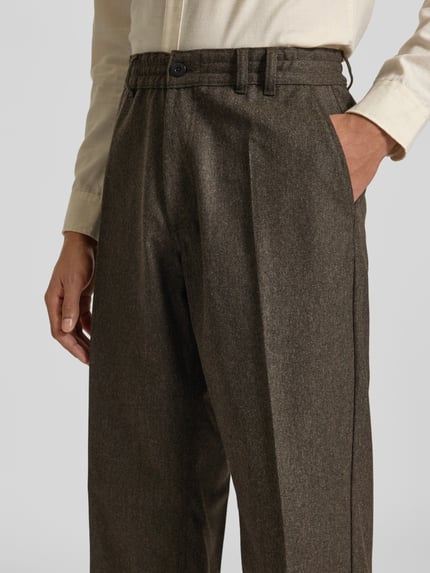 Männermodel trägt Straight Fit Anzughose aus Woll-Mix von Forét, Bundfalten, Eingriff- und Gesäßtaschen, Nahaufnahme Oberkörper.