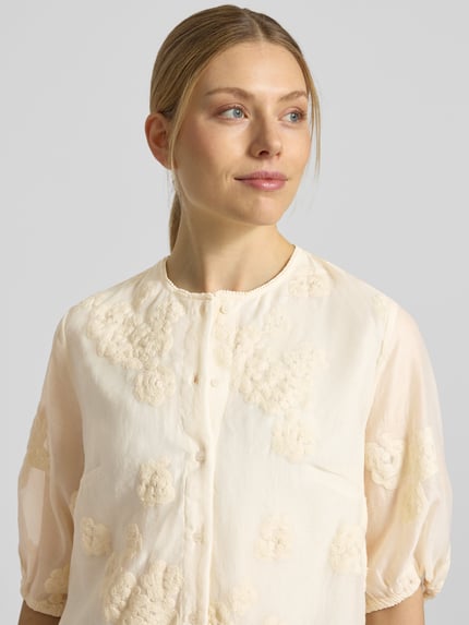 Frauenmodel trägt Regular Fit Bluse mit floralem Zierbesatz von Jake*s Collection in Creme, Baumwoll-Mix, Nahaufnahme Oberkörper.