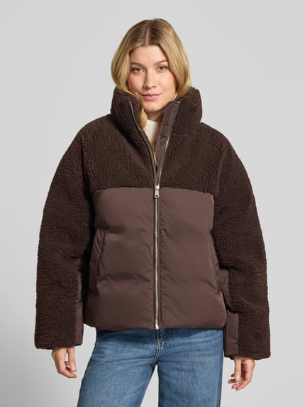 Frauenmodel trägt Steppjacke Modell 'Hazy' mit Fleece-Einsätzen von OPUS in Dunkelbraun, Stehkragen, Reißverschluss, seitliche Eingrifftaschen, langarm, elastische Abschlüsse, kombinierte Webware und Fleece, unifarben, Ganzkörperansicht von vorne.