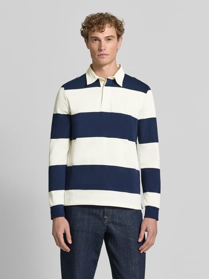 Männermodel trägt Poloshirt aus reiner Baumwolle von Christian Berg Men, weite Streifen in Dunkelblau und Creme, lockere Passform, Ganzkörperansicht von vorne