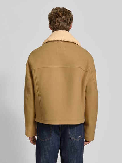 Männermodel trägt Jacke mit Logo-Stitching und Pattentaschen von Emporio Armani in Beige, Wolloptik, Rückenansicht, Ganzkörperansicht von hinten.