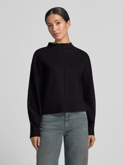 Frauenmodel trägt Strickpullunder Modell 'Punus' mit Mock Neck von OPUS, unifarben, hochgeschlossen, ohne Ärmel, abgerundeter Abschluss, Ganzkörperansicht von vorne.