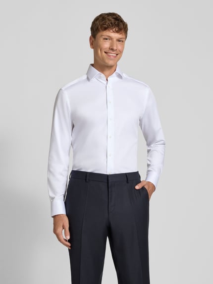 Männermodel trägt weißes Modern Fit Businesshemd aus reiner Baumwolle Modell 'Global Kent' von OLYMP, Ganzkörperansicht von vorne.
