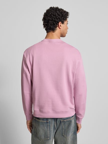 Männermodel trägt Sweatshirt aus reiner Baumwolle von Calvin Klein Jeans in Rosa mit geradem Schnitt und gerippten Abschlüssen, Ganzkörperansicht Rückansicht.
