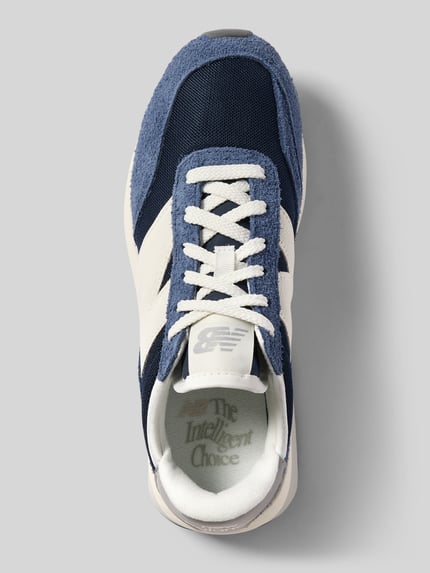 Produktfoto, Sneaker mit Label-Details Modell 'U370' von New Balance in Dunkelblau und Weiß, abgerundete Form, Schnürung, strukturierte Sohle, Absatzhöhe 5 cm, Schafthöhe 7 cm, Schaftweite 7 cm, textile und strukturierte Texturen.