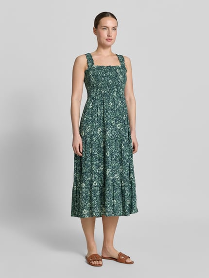 Frauenmodel trägt Midikleid aus Viskose mit Karree-Ausschnitt von Apricot, Taillierter Schnitt, Rüschen, Breite Träger, Volantsaum, Ganzkörperansicht von vorne.