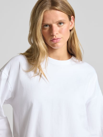 Frauenmodel trägt Oversized Langarmshirt aus reiner Baumwolle von REVIEW, Damen Langarmshirt, weiß, glatte Textur, Nahaufnahme Oberkörper.