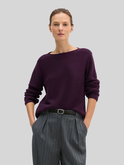 Frauenmodel trägt Regular Fit Pullover aus reiner Baumwolle von MARC O'POLO in unifarbener, dunkelvioletter Strickoptik, Nahaufnahme Oberkörper.