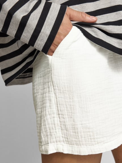 Frauenmodel trägt Relaxed Fit Shorts aus reiner Baumwolle Modell 'THYRA' von Only, Optik: Unifarben, Crêpe-Textur, seitliche Eingrifftaschen, Nahaufnahme Oberkörper.