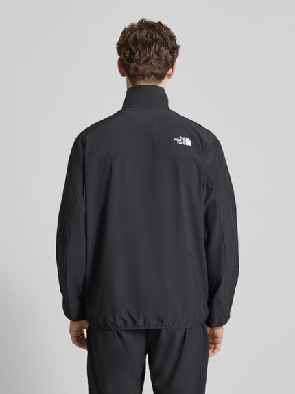 Männermodel trägt Regular Fit Jacke mit Stehkragen Modell 'Mountain' von The North Face in Schwarz, Elastischer-Material-Mix, Logo-Print, Reißverschluss, Eingrifftaschen, elastische Abschlüsse, Rückenlänge 73 cm, Schulterbreite 43 cm, Brustweite 56 cm, Ärmellänge 70 cm, Ganzkörperansicht Rückansicht.