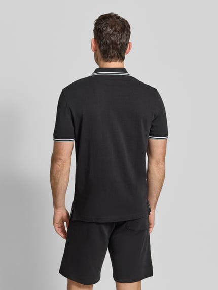 Męski model nosi Regular Fit Poloshirt mit Kontraststreifen od Christian Berg Men, czarna bawełna, krój regular fit, widok całej sylwetki od tyłu.