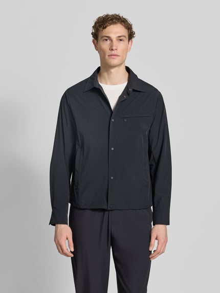 Männermodel trägt Blouson mit Kentkragen und Brusttasche von ARMANI EXCHANGE in Dunkelblau, glatte Struktur, Ganzkörperansicht von vorne. Material-Mix mit Stretch, Regular Fit, Knopfleiste, Reißverschluss-Brusttasche, Rückenlänge bei Größe M 66 cm.