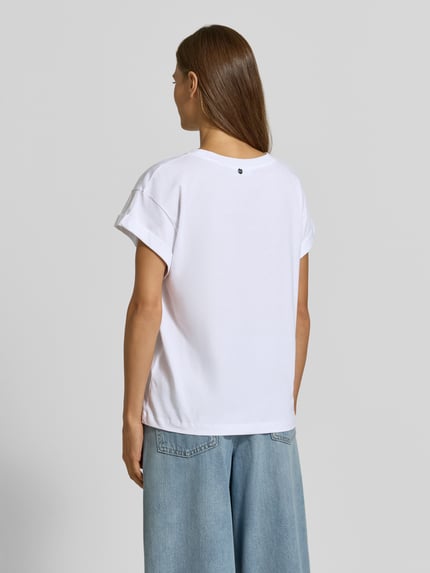 Frauenmodel trägt T-Shirt aus reiner Baumwolle von Rich & Royal, lockere Passform, weiße Farbe, glatte Textur, Ganzkörperansicht Rückansicht.